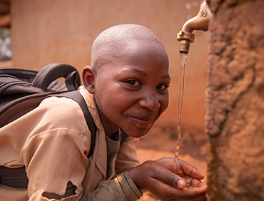 black-schoolchild-collects-water-with-his-hands-fr-UGYHXEN